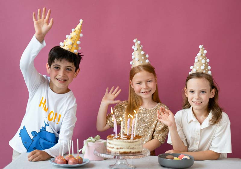 crianças acenando felizes em uma mesa decorada de festa