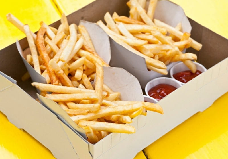 um box de papelão com embalagens de papel para batas fritas dentro com ketchup