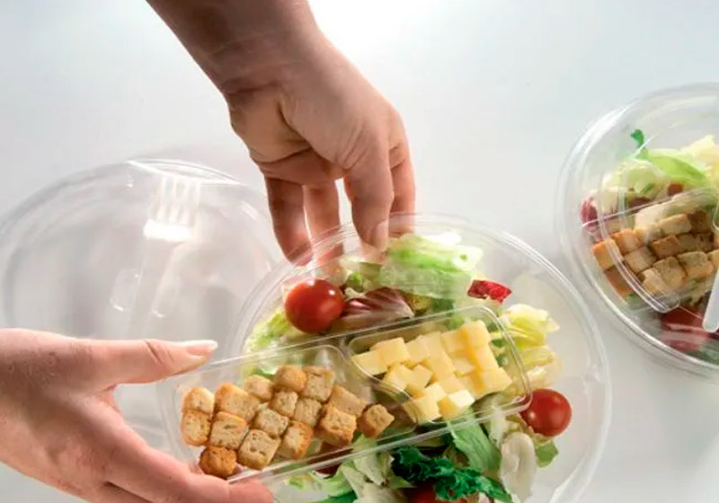 Pessoa manuseando embalagem descartável transparente com comida